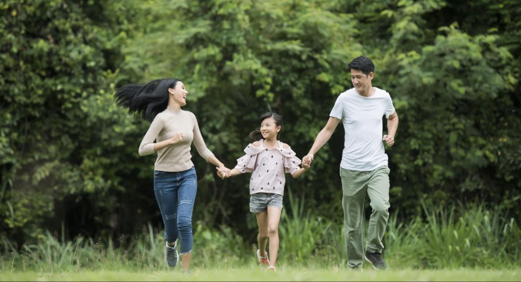 Happy family running together outdoors, showing improved vision after amblyopia lazy eye treatment for adults
