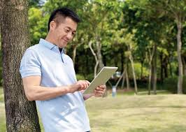 Man reading about refractive lens exchange vs LASIK options outdoors on a tablet