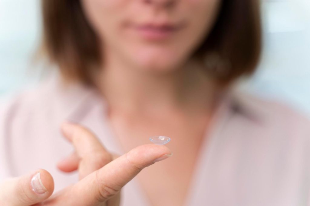 Woman examining a contact lens alternative while considering refractive lens exchange pros and cons for long-term vision correction.