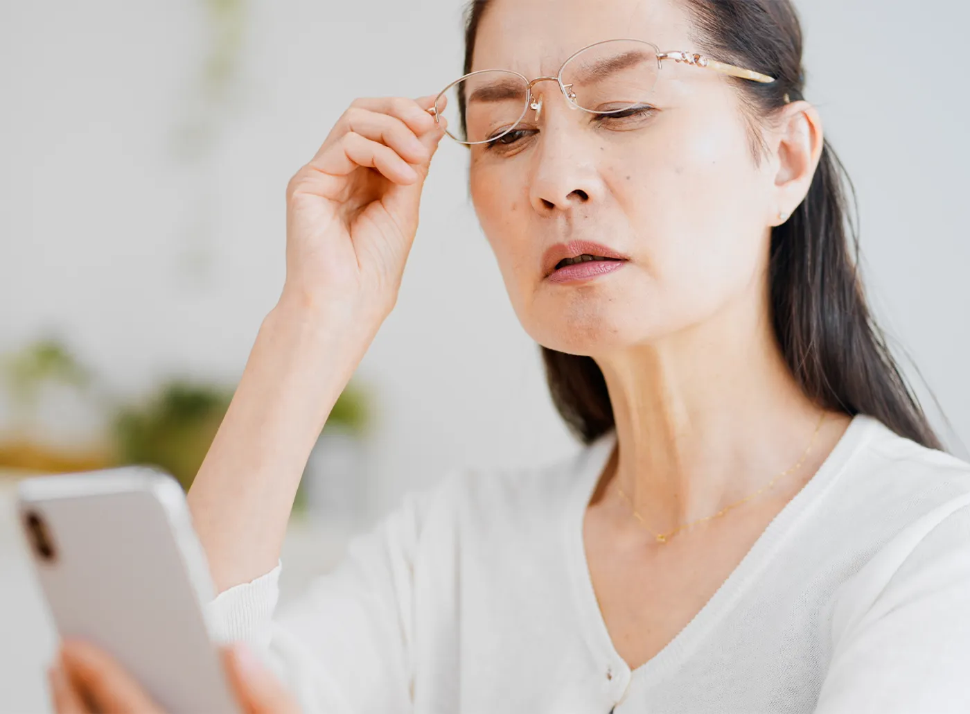a woman struggling to look closely at her phone