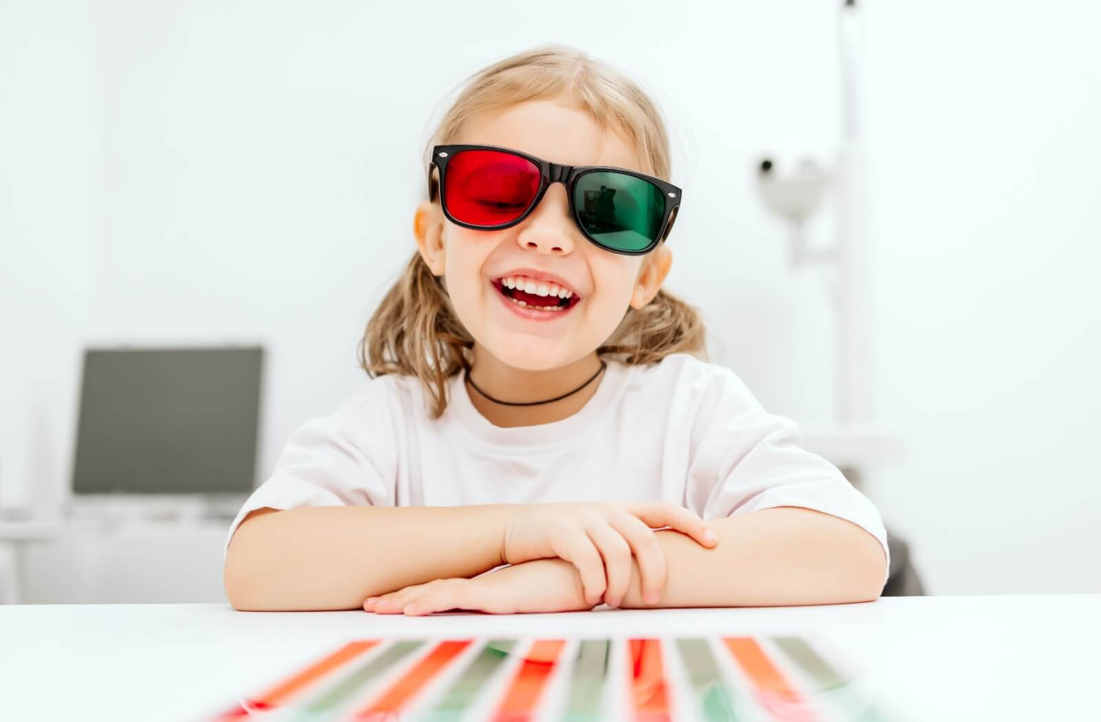 A laughing girl wears red-green dichoptic glasses used in modern amblyopia treatment