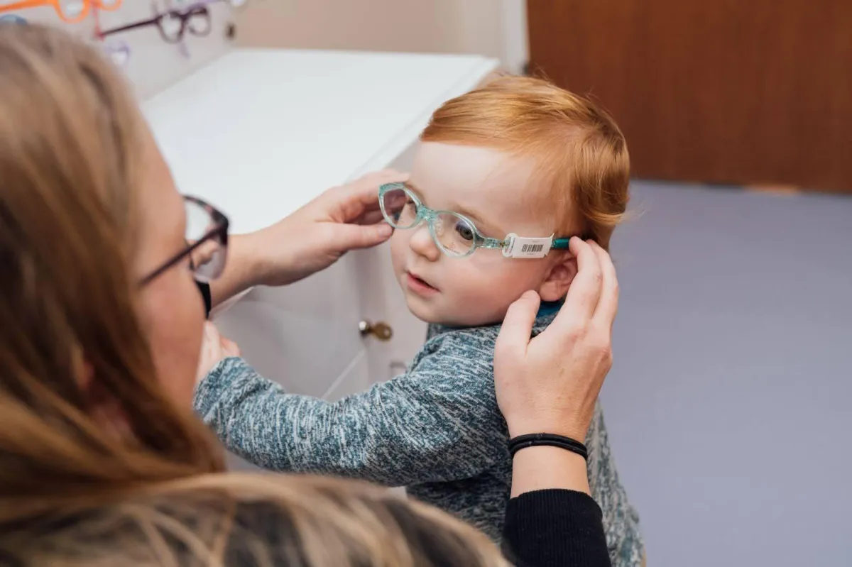 a doctor helping child to wear spec