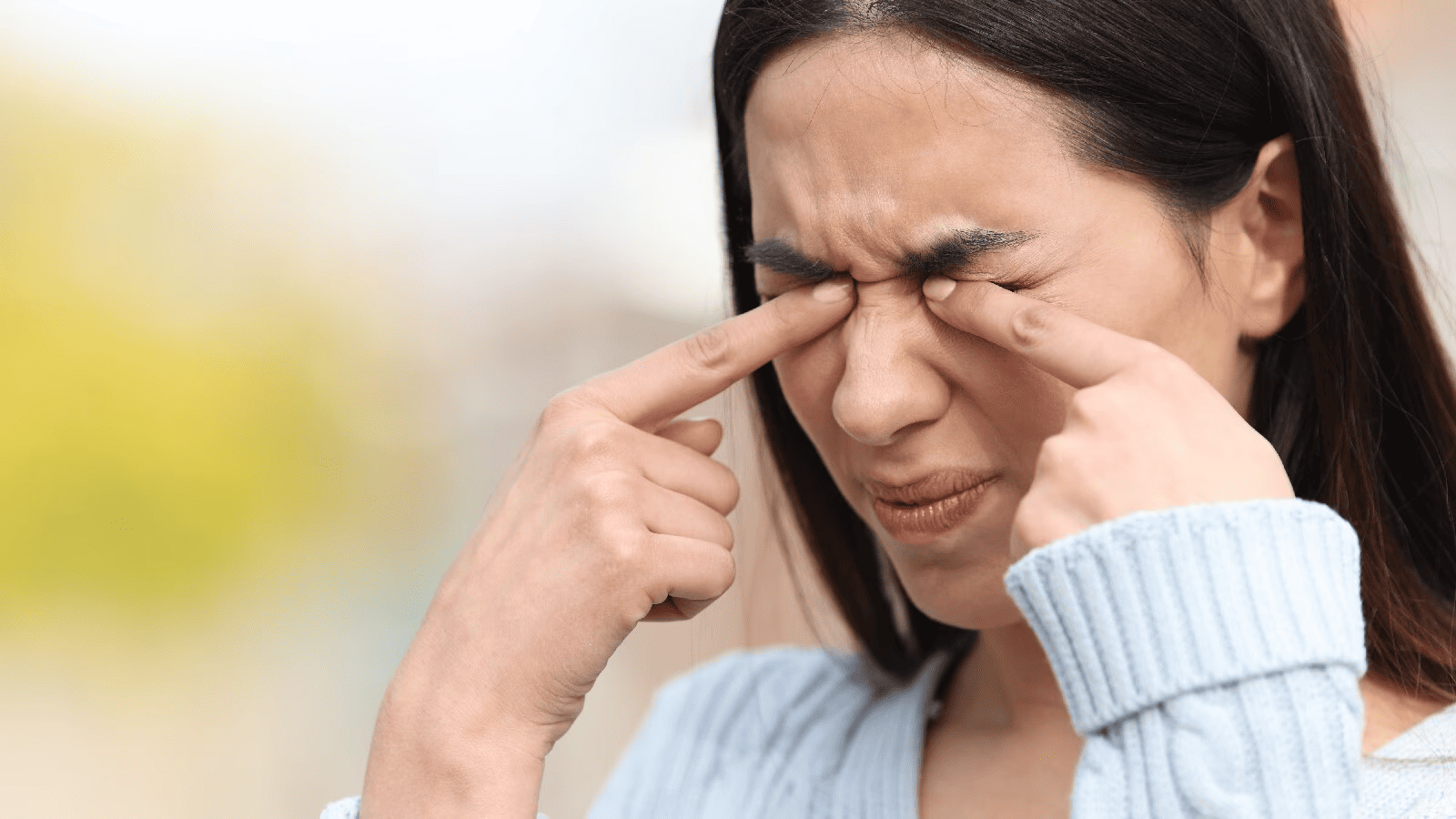 A woman rubbing her itchy eyes with both hands